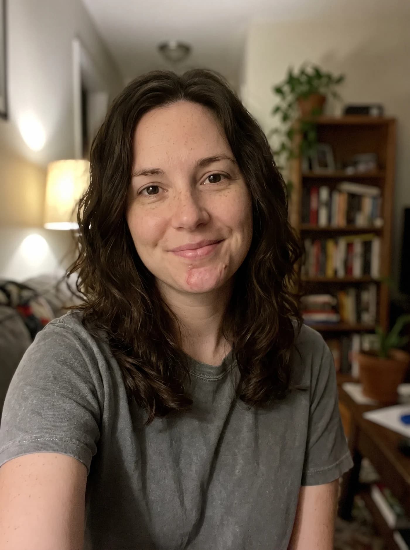 A casual evening selfie of a woman with wavy dark hair, on her couch.