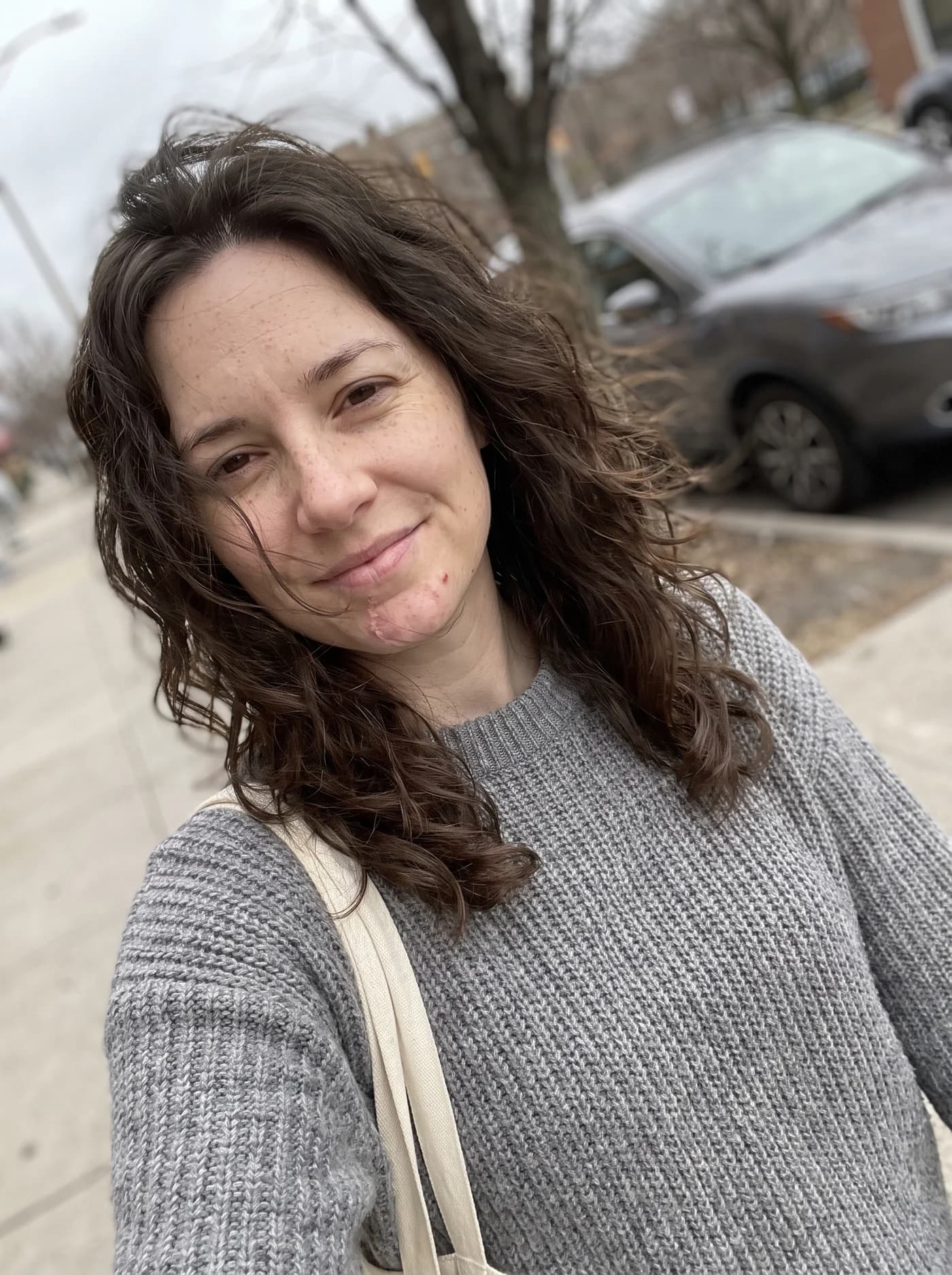 A second selfie of her, outside on an overcast street.